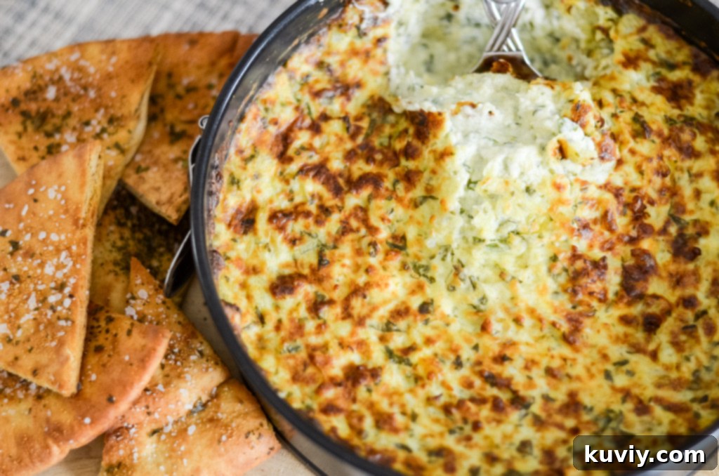 Air fryer spinach dip served beautifully with a variety of dippers including pita chips and fresh vegetables, with a sprinkle of red pepper flakes.