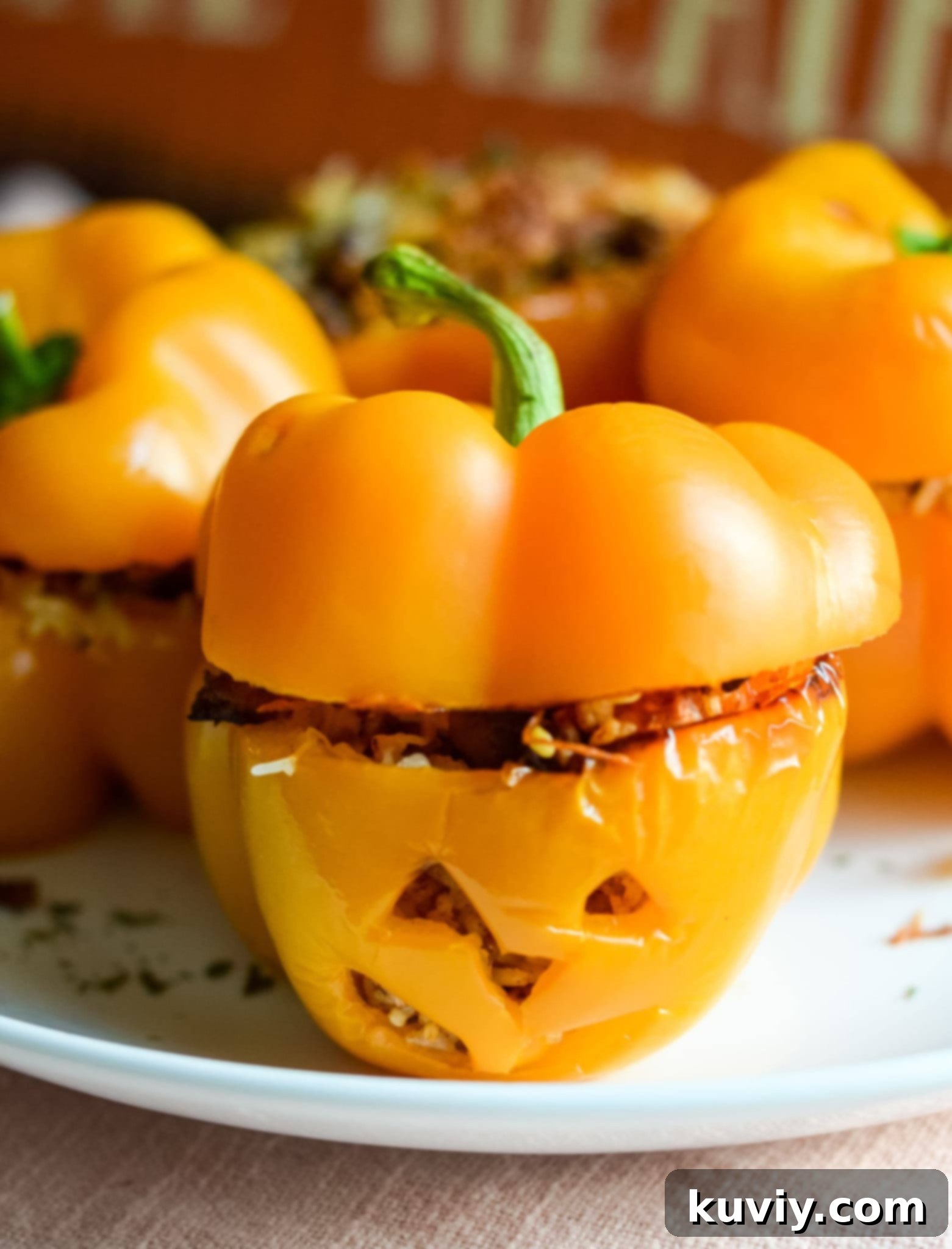 Air Fryer Stuffed Pumpkin Peppers in an air fryer basket, shaped like Jack-O-Lanterns.