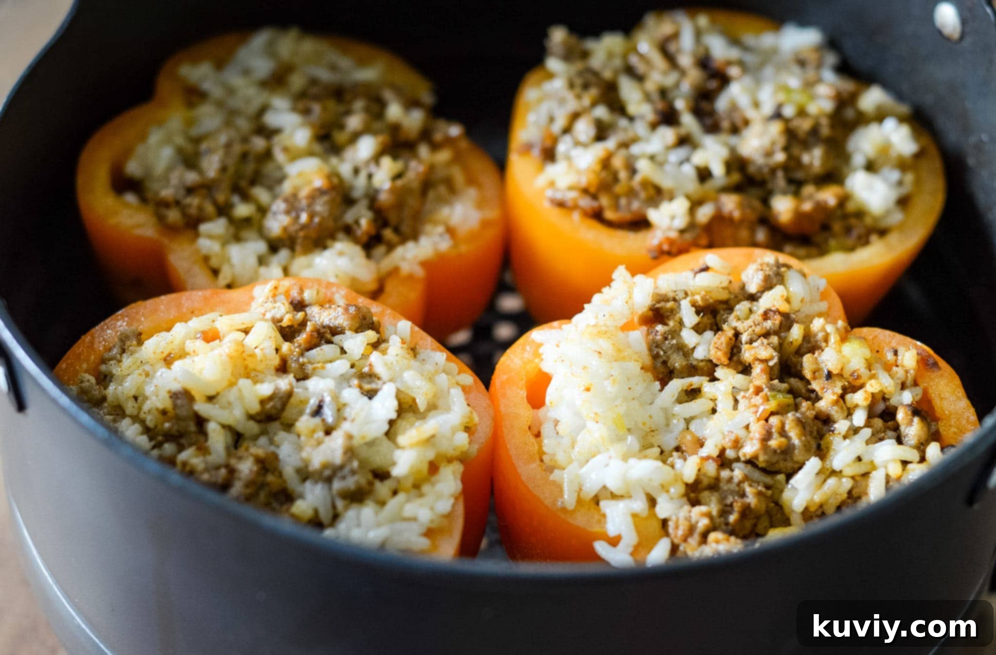 Close-up of a carved orange bell pepper with a Jack-O-Lantern face, ready to be stuffed.