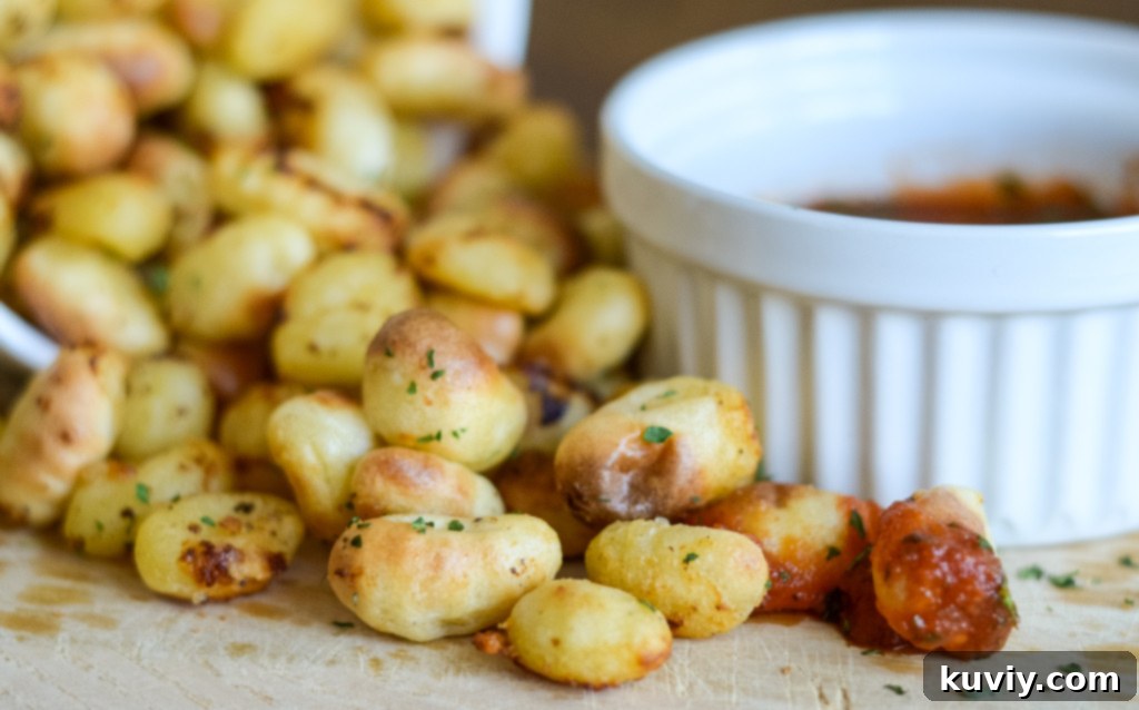 Air fryer basket filled with frozen gnocchi being sprayed with oil
