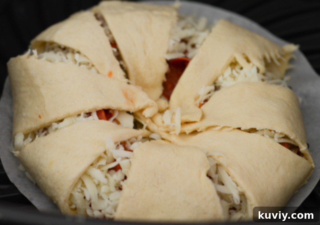Air fryer pizza ring cooking in an air fryer basket lined with parchment paper