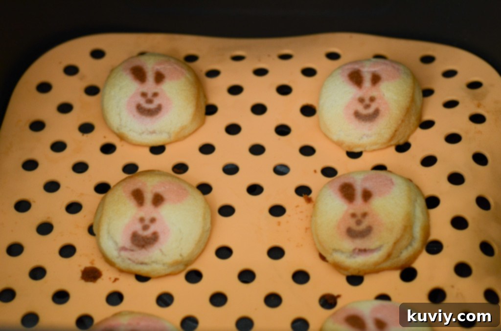 Air fryer basket with Pillsbury sugar cookies baking on a silicone mat