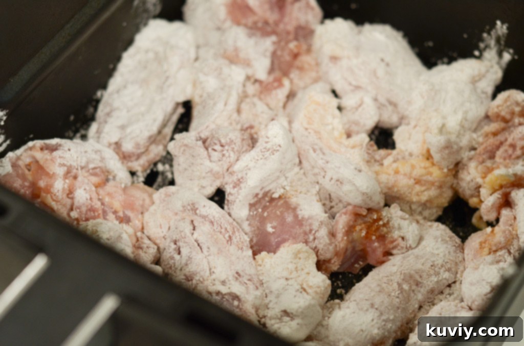 Crispy Hot Honey Air Fryer Chicken Bowls 4 The cooking process shown with coated chicken pieces being placed into an air fryer basket in a single layer.