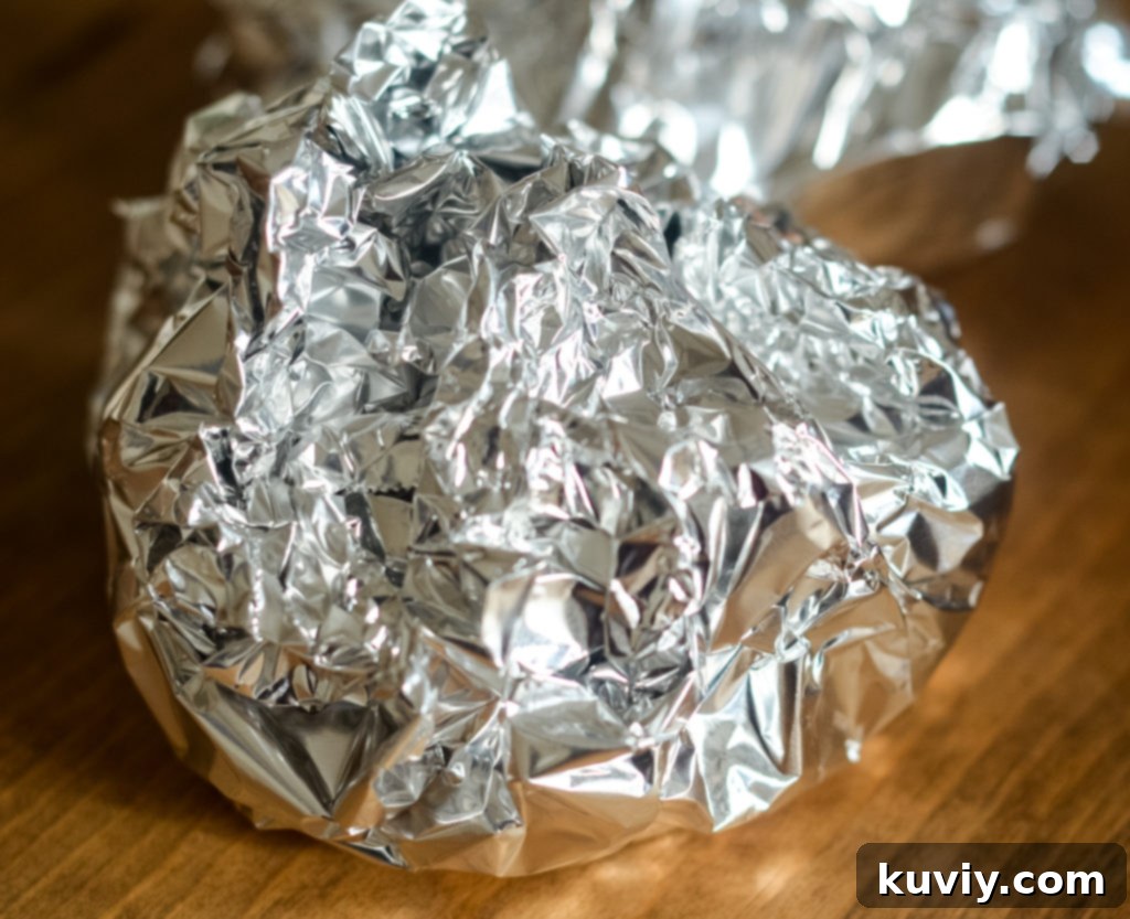 Sealed foil packets cooking inside an air fryer basket