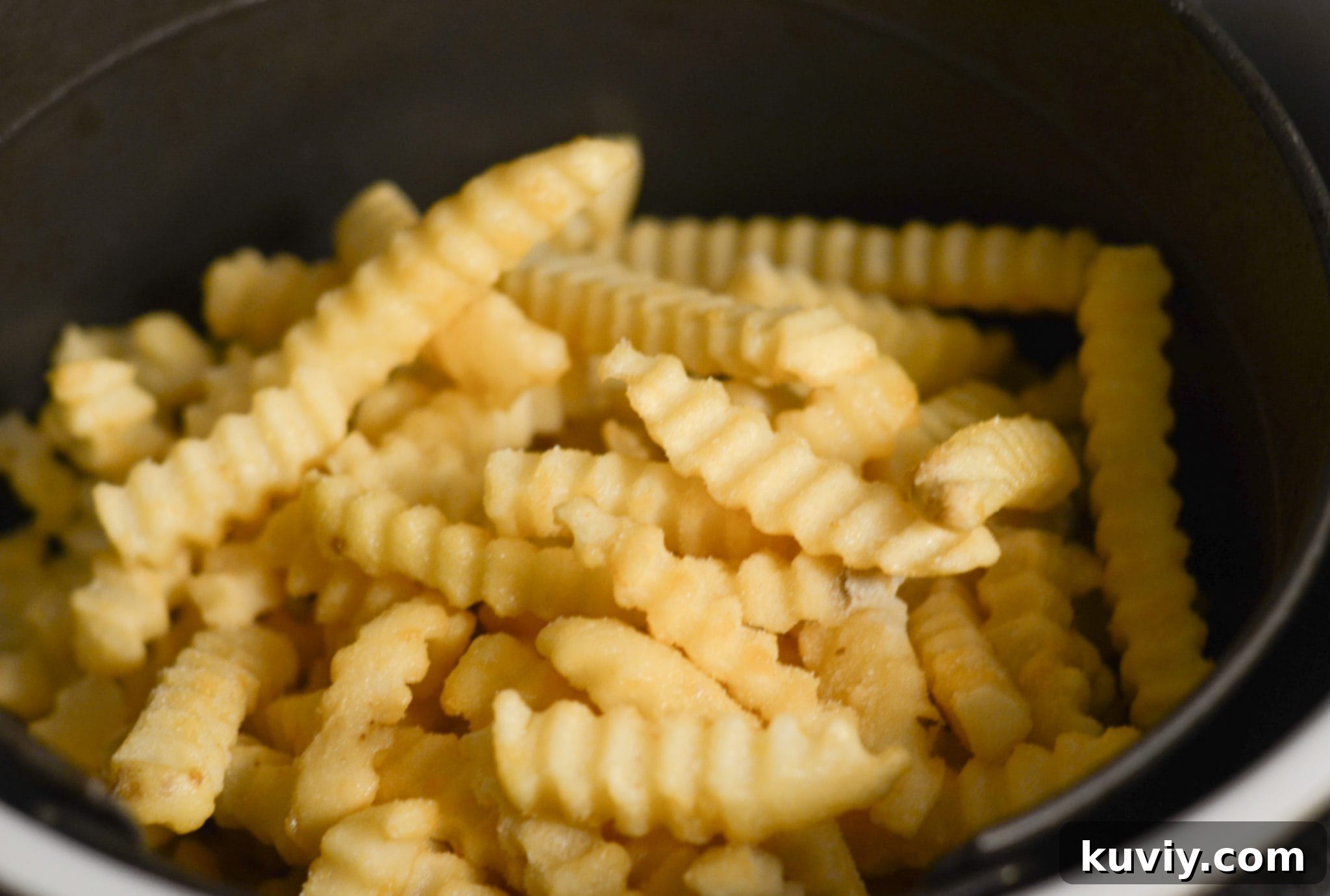 Easy Air Fryer Frozen French Fries: Crispy Perfection 3 Frozen French fries being placed into an air fryer basket