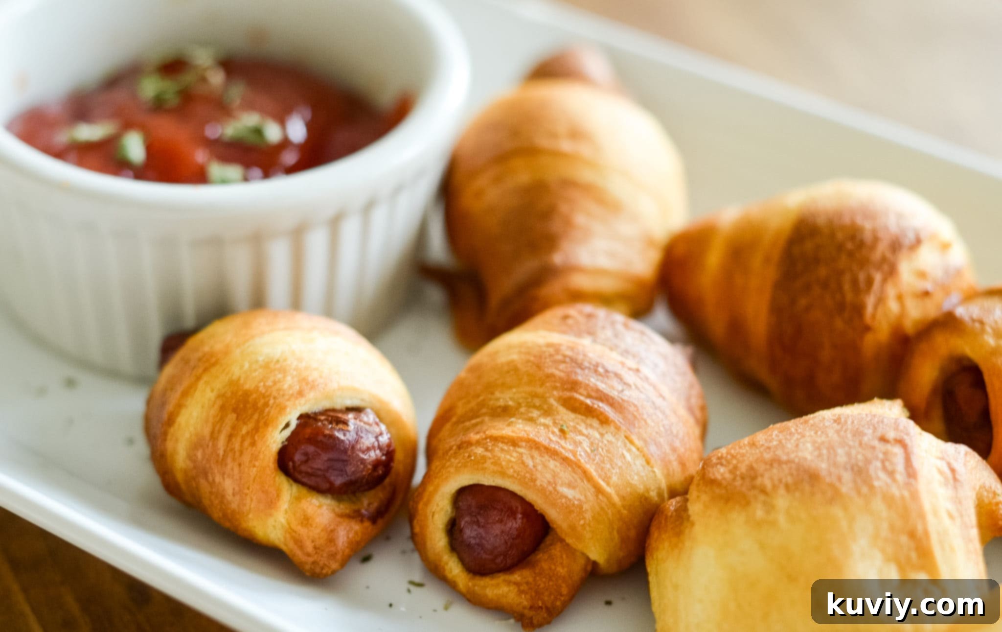 Crispy Air Fryer Pigs in a Blanket 4 Freshly cooked golden Air Fryer Pigs in a Blanket in the air fryer basket.
