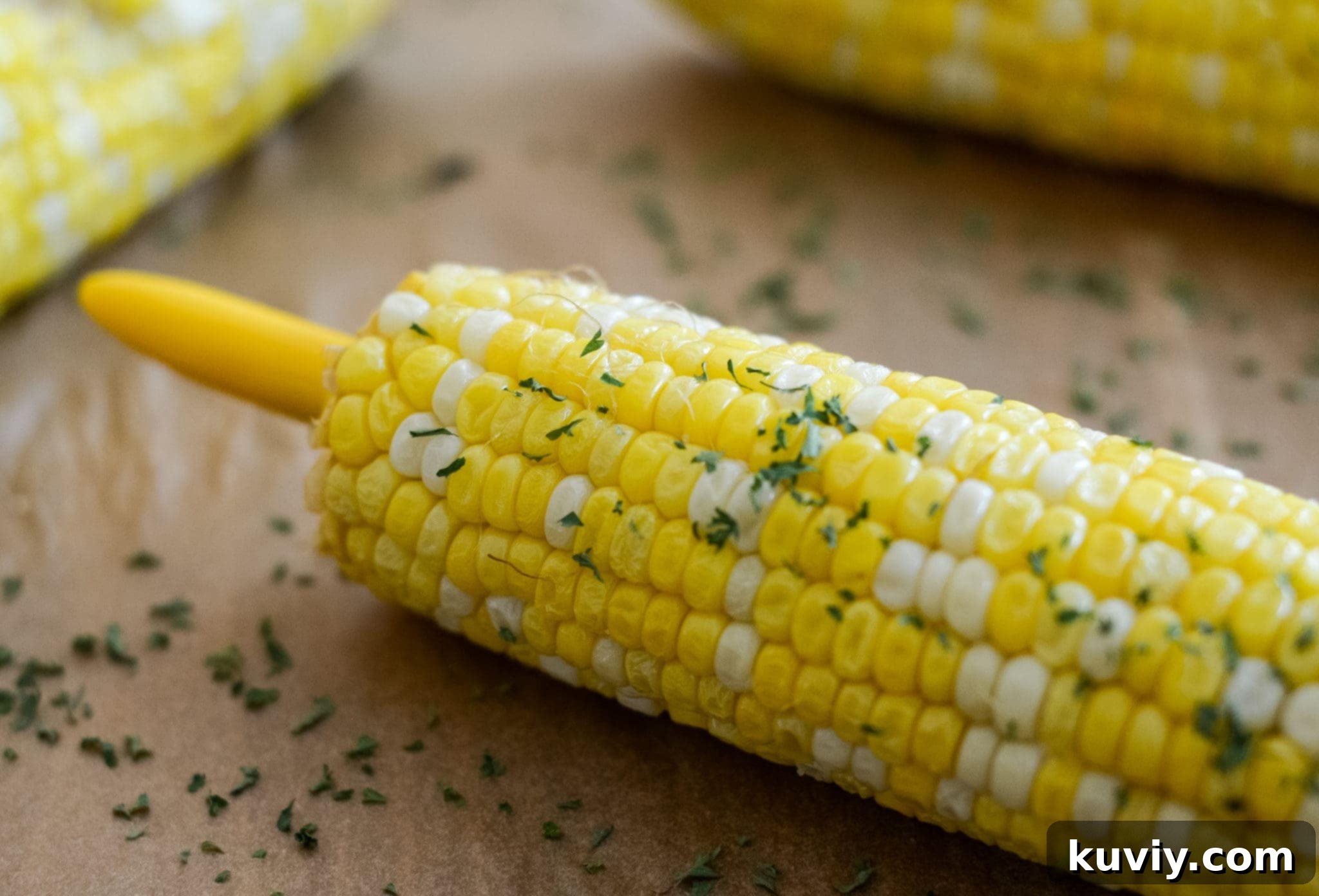 Close-up of perfectly cooked air fryer corn on the cob, garnished and ready to serve on a rustic wooden board