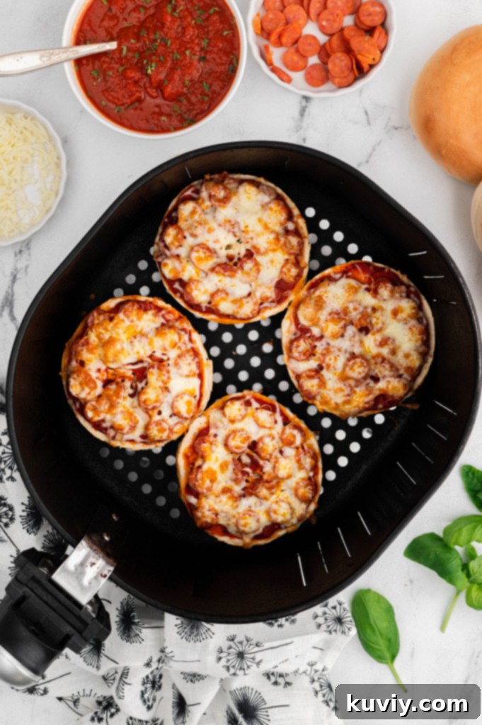 Hands spreading pizza sauce onto a halved bagel, preparing it for air frying