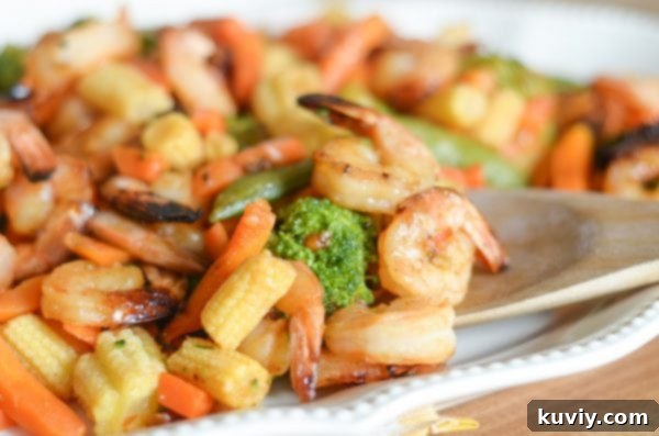 Close-up of plated air fryer honey garlic shrimp with mixed stir-fry vegetables, garnished for serving