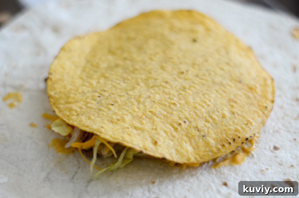Layering taco meat, cheese, and fresh toppings onto a tostada shell