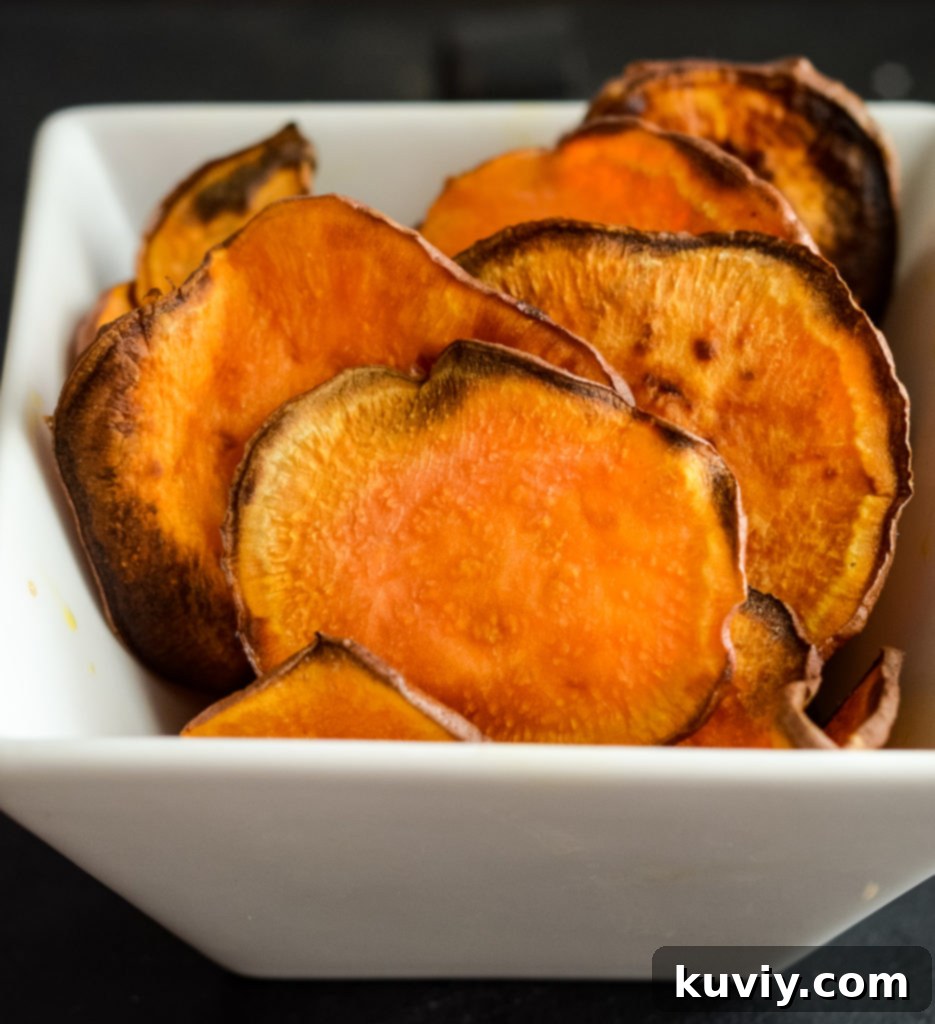 Air fryer sweet potato chips arranged beautifully in a wooden bowl with a rustic linen napkin, ready to be enjoyed.