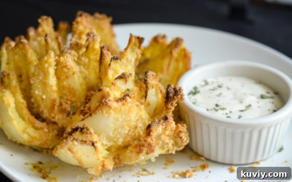 Gluten-free air fried blooming onion on a serving plate with dipping sauce.