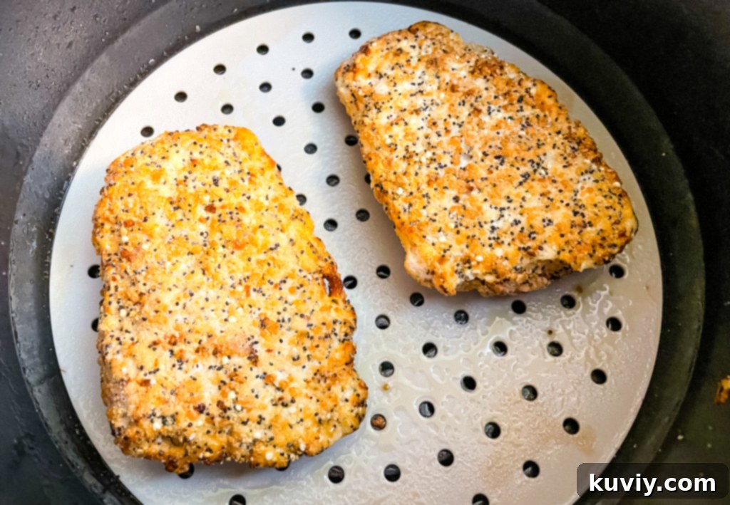 Air fryer basket with perfectly cooked and golden-brown cod fillets inside