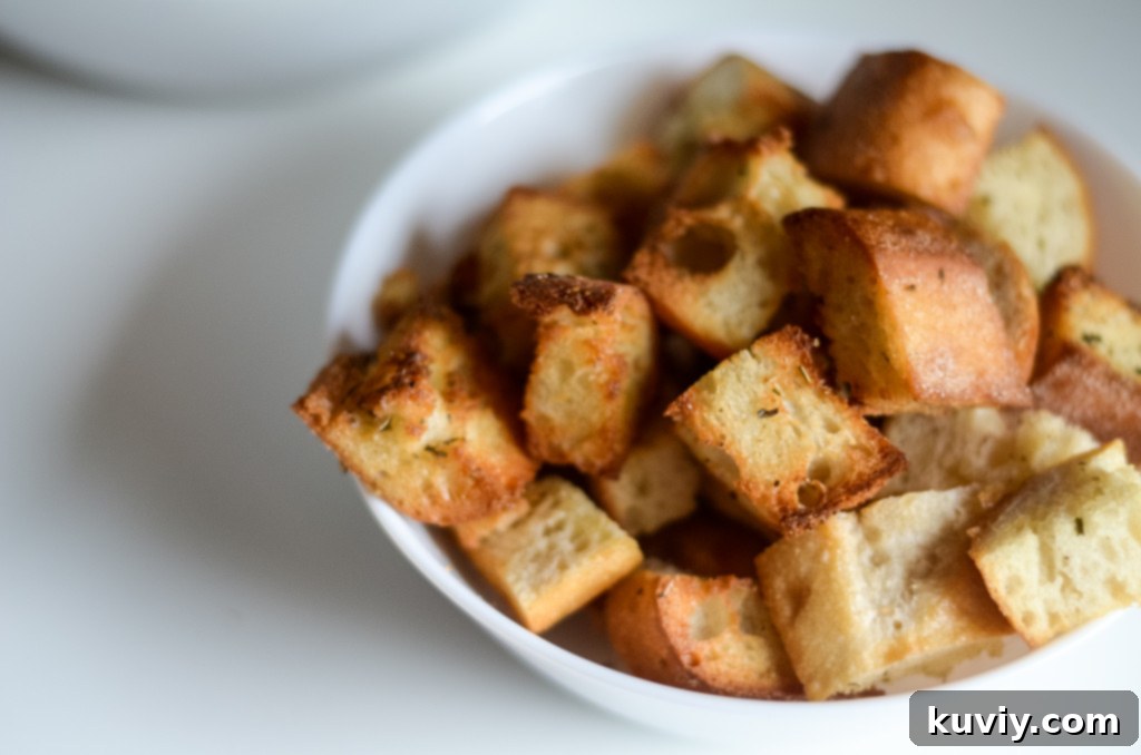 Air fryer croutons being tossed with olive oil and Italian seasoning in a bowl