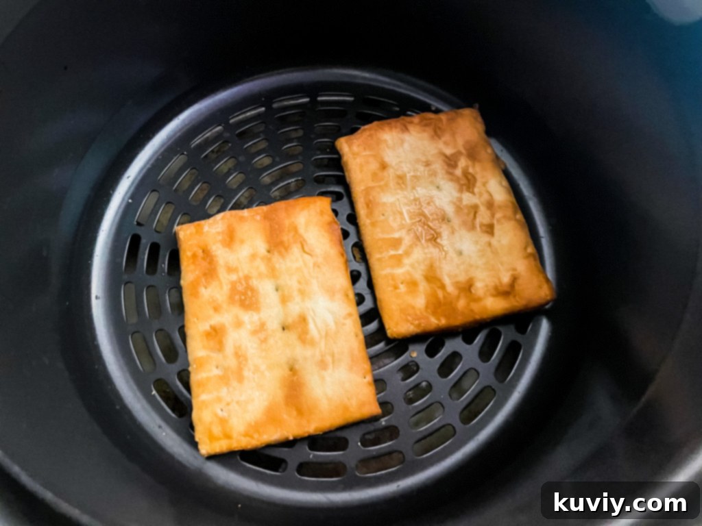 Air Fryer Toaster Strudel Hack 3 Two Toaster Strudels cooking to a perfect golden crisp in an air fryer basket.