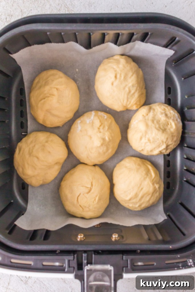 Air fryer basket lined with parchment paper, ready for dinner roll dough