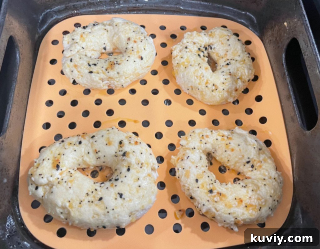 Hands rolling bagel dough into a snake shape on a cutting board