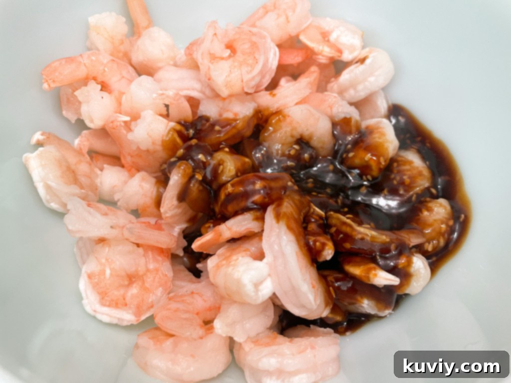 Air Fryer Sesame Shrimp being coated in the rich, glossy sauce