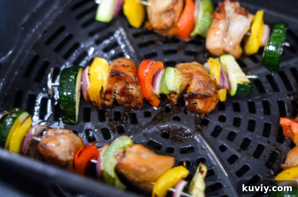 Two air fryer chicken kabobs cooling in an air fryer basket after cooking