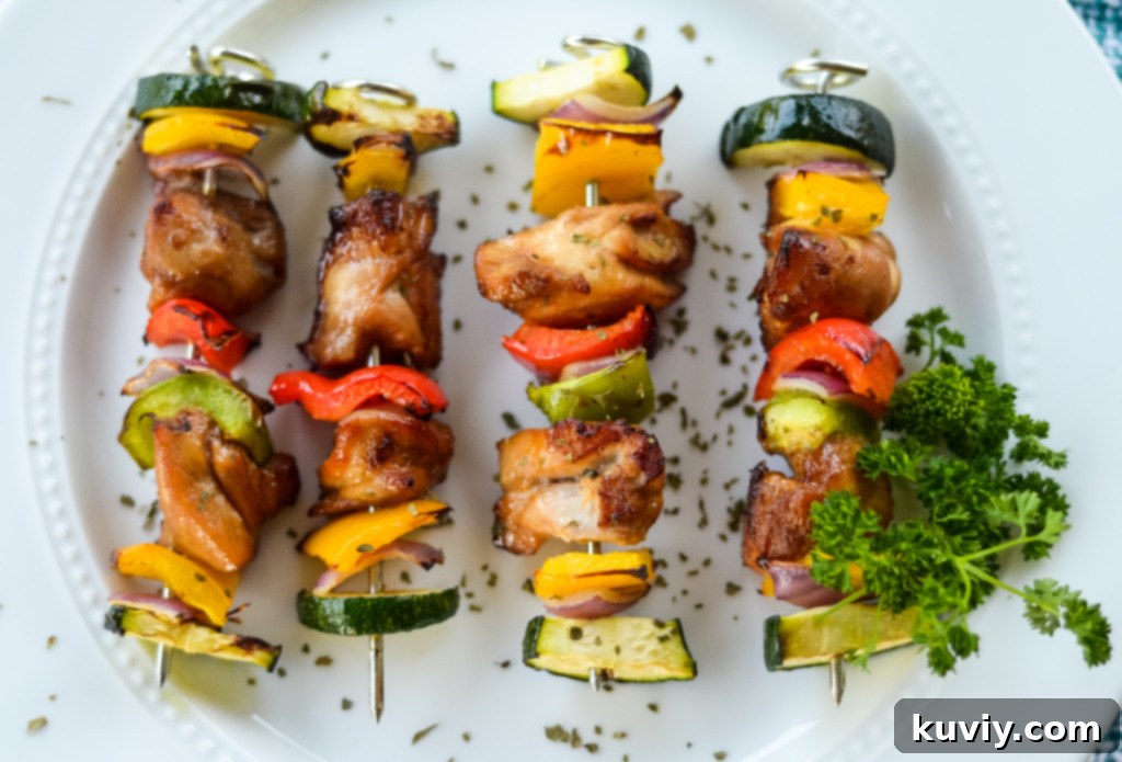 Assembling air fryer chicken kabobs with marinated chicken and various chopped vegetables on metal skewers