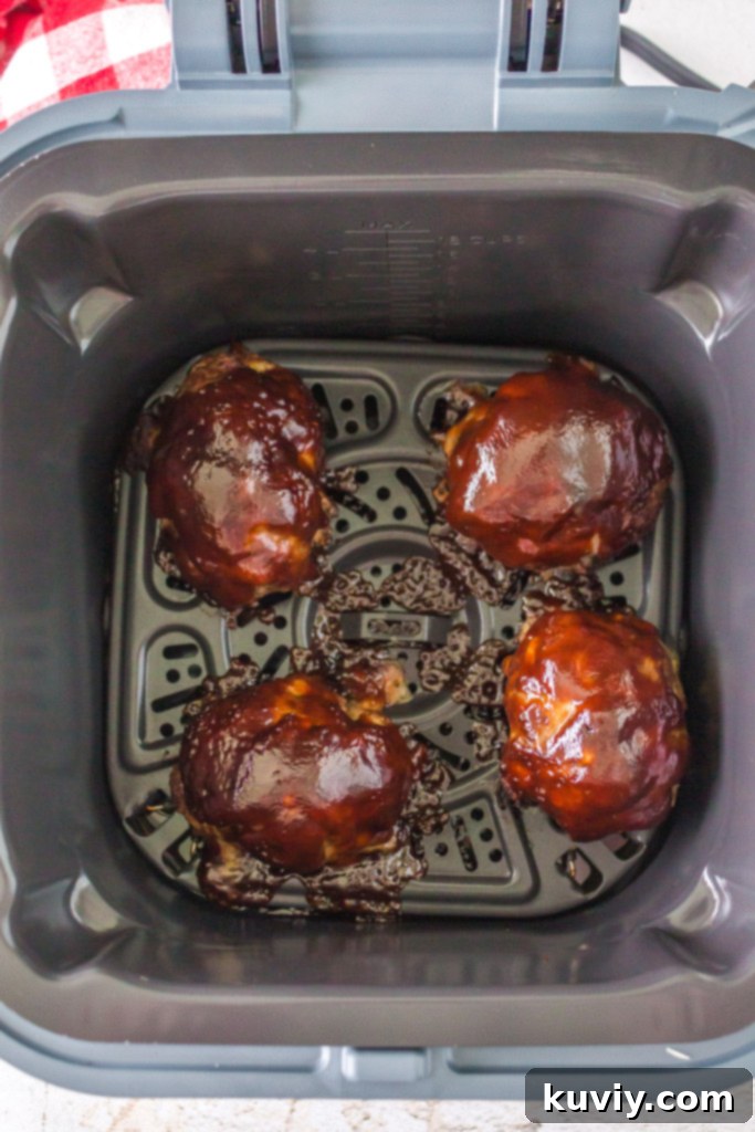 A digital meat thermometer inserted into a cooked mini meatloaf to check its internal temperature.