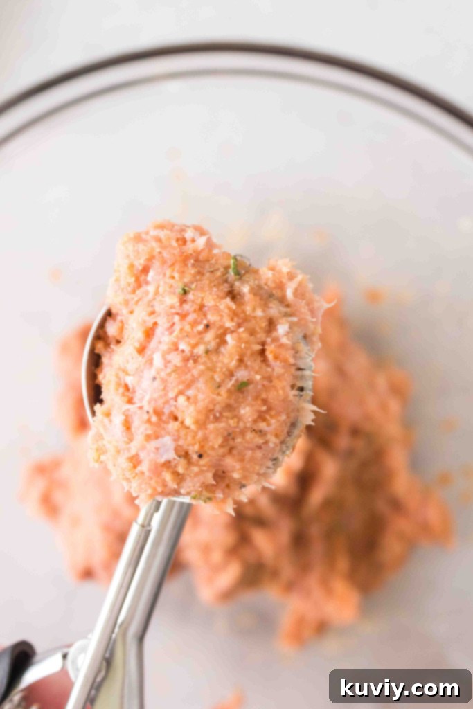 Raw ingredients for turkey meatballs in a mixing bowl, including ground turkey, spices, breadcrumbs, and an egg