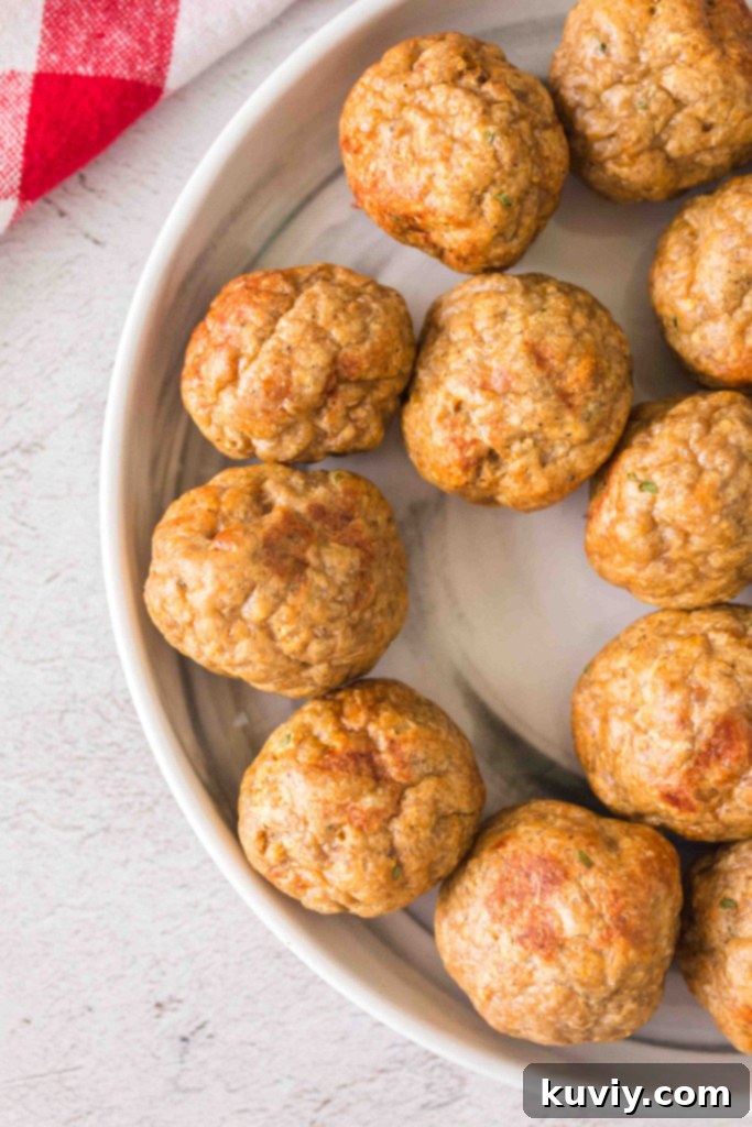 A bowl of sauced air fryer turkey meatballs, garnished with fresh herbs
