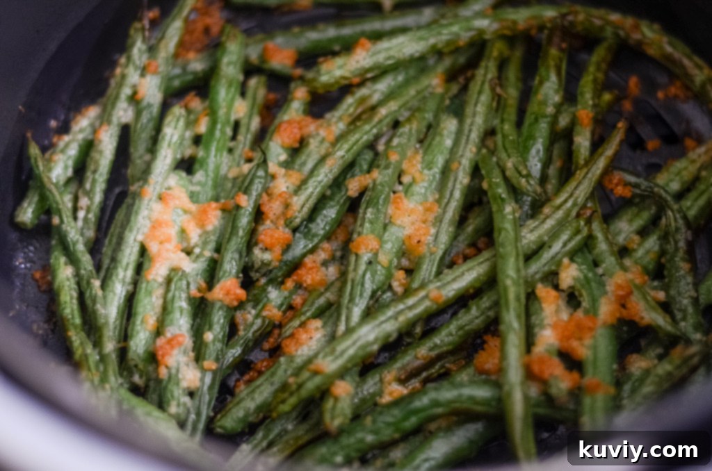 close-up of air fryer parmesan green beans with garlic and oil