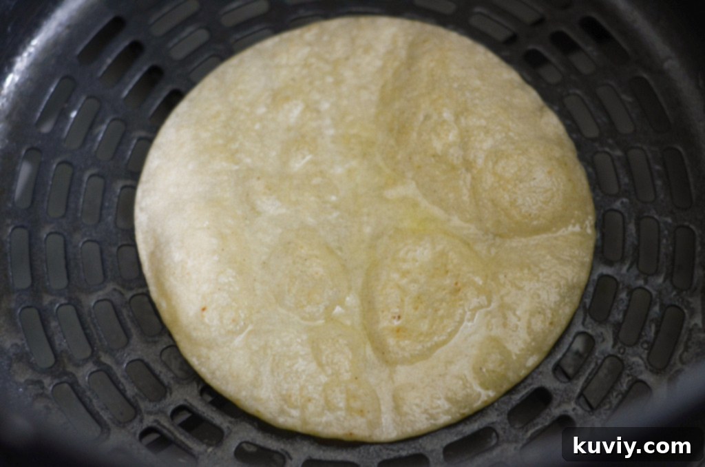 Corn tortillas in an air fryer basket being cooked