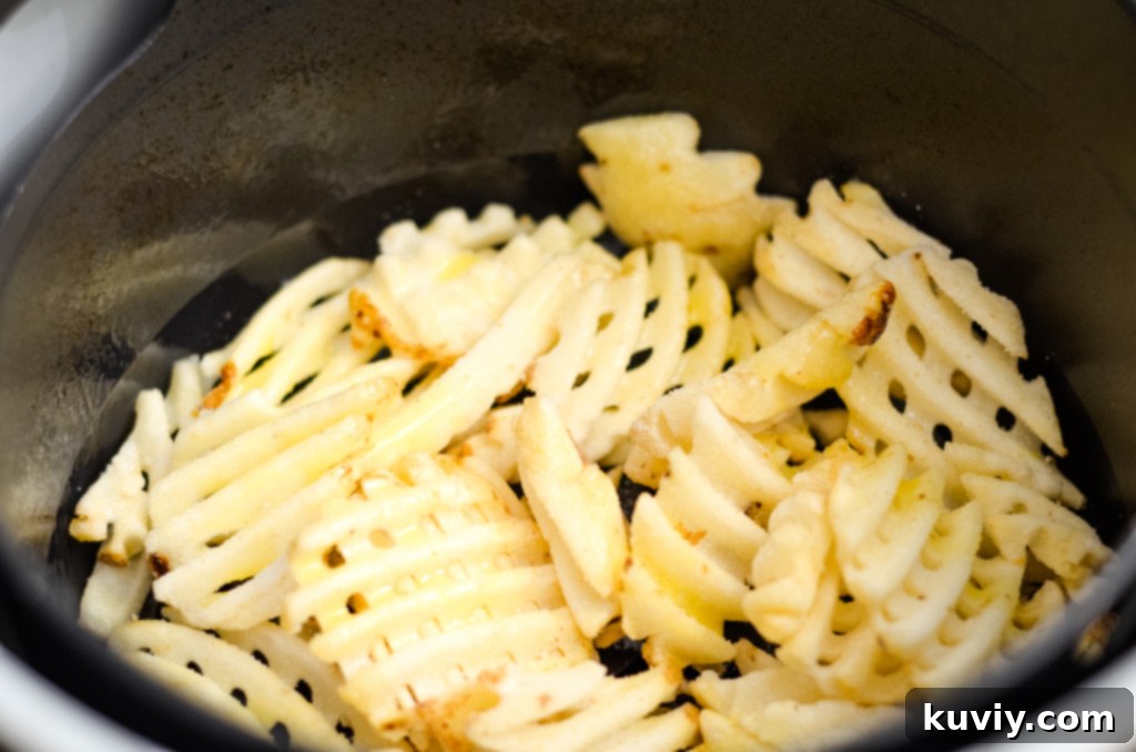 Air frying waffle fries in the basket, showing even cooking