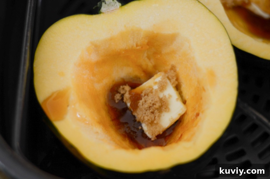 Acorn squash halves with butter and brown sugar in air fryer basket